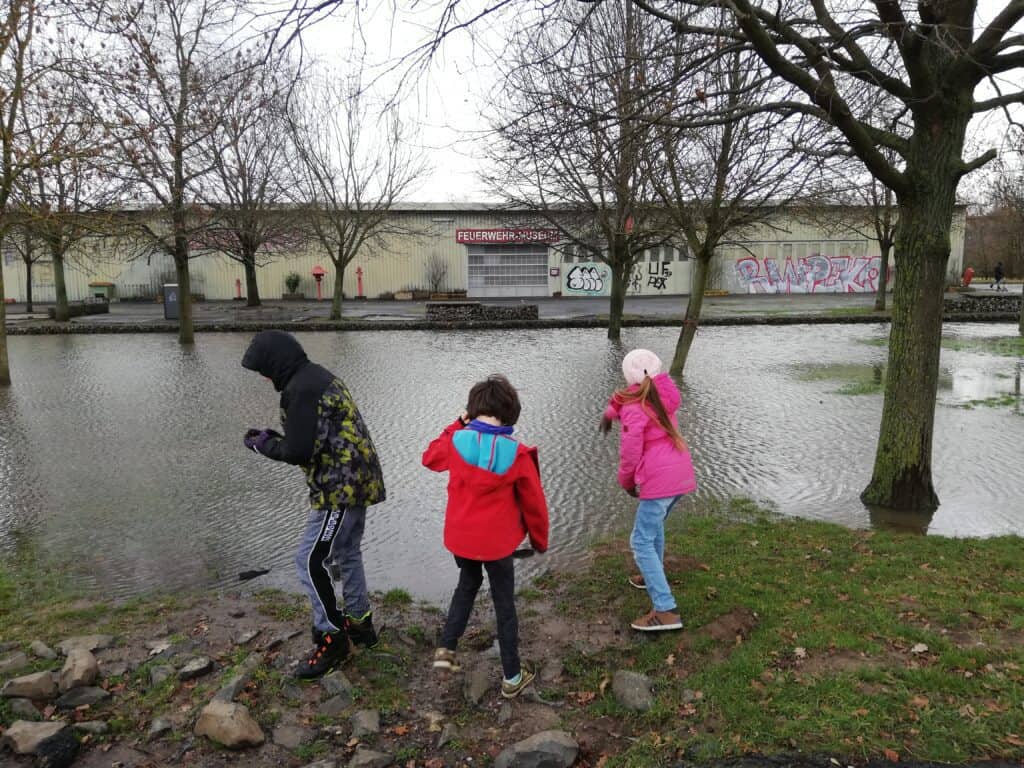 12 von 12 Kinder werfen Steine in den See